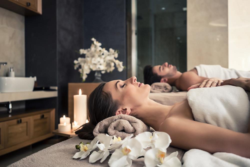 A man and woman lying down on massage beds at a spa