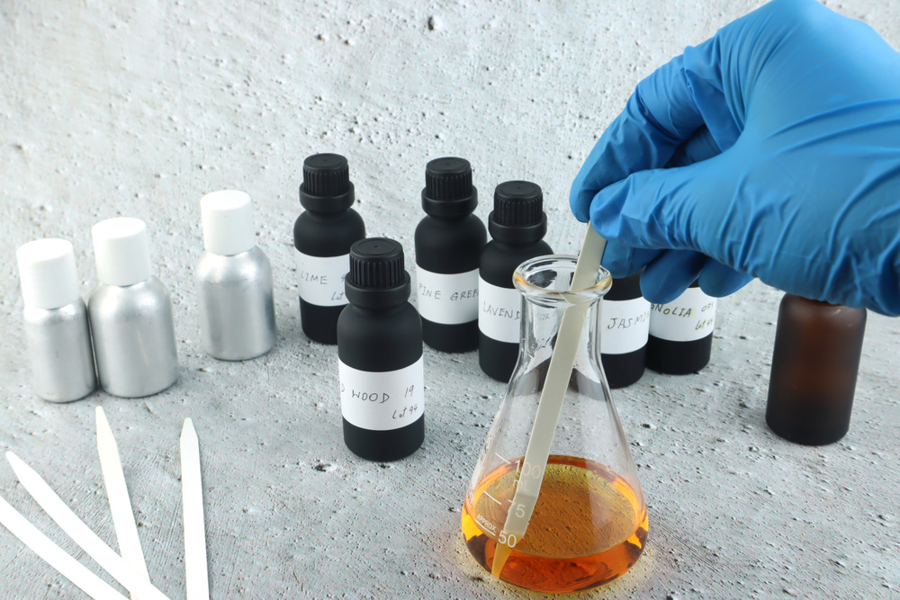 Chemical beaker , flask is on white table with blotting paper , fragrance bottle and essential oil bottle are used to blend the nice scent for making perfume
