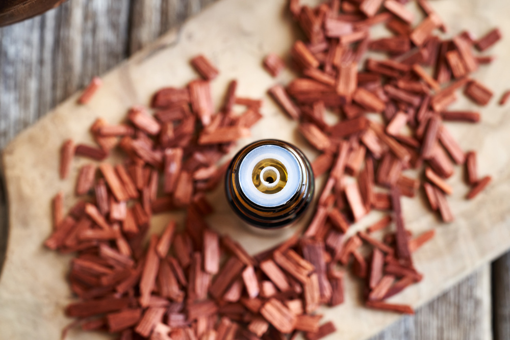 Red sandalwood oil in a brown glass bottle on a table, top view