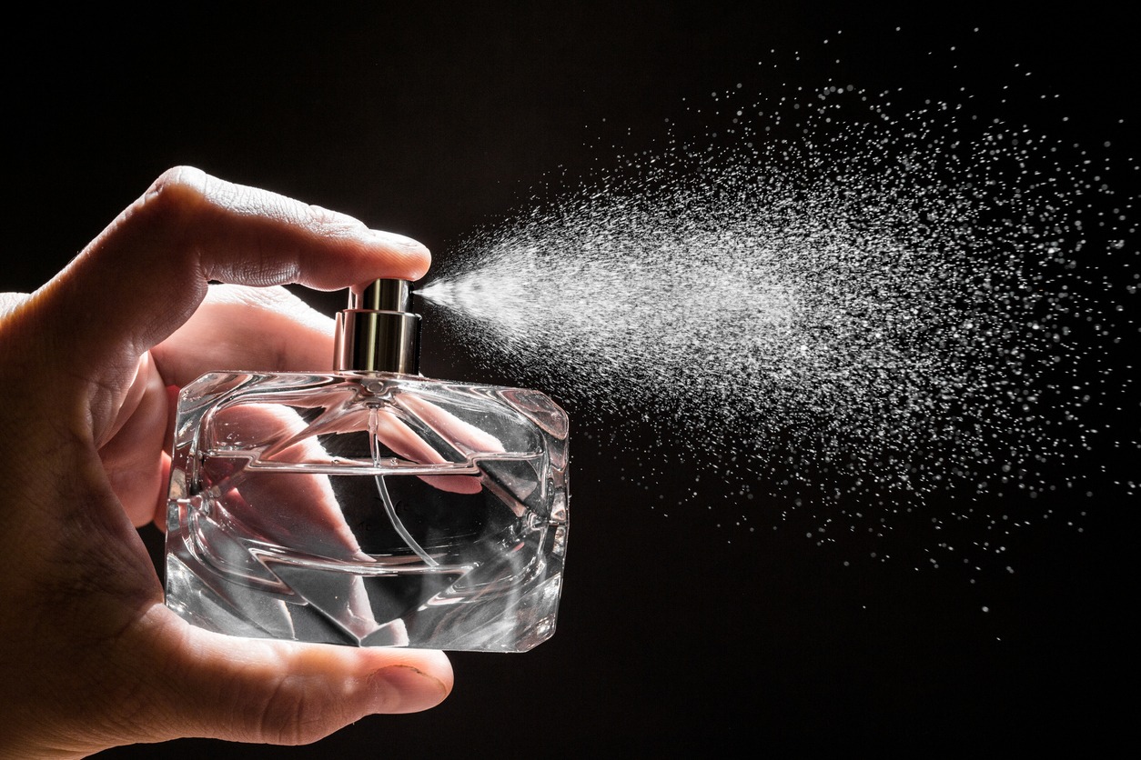 spraying perfume on dark background, closeup - Image