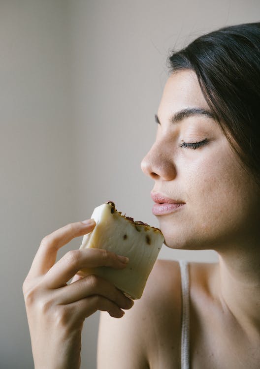 a woman with her eyes closed holding a soap bar near her face
