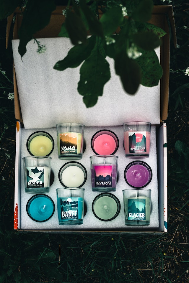 a box of colorful candles in glass jars