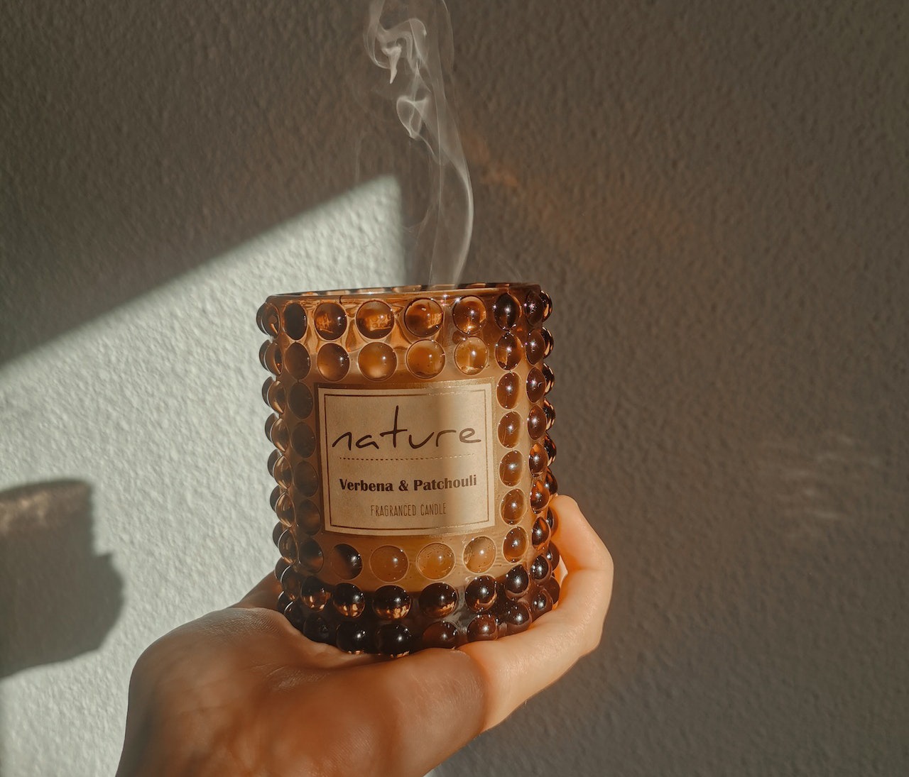 a person holding a glass jar with scented candle