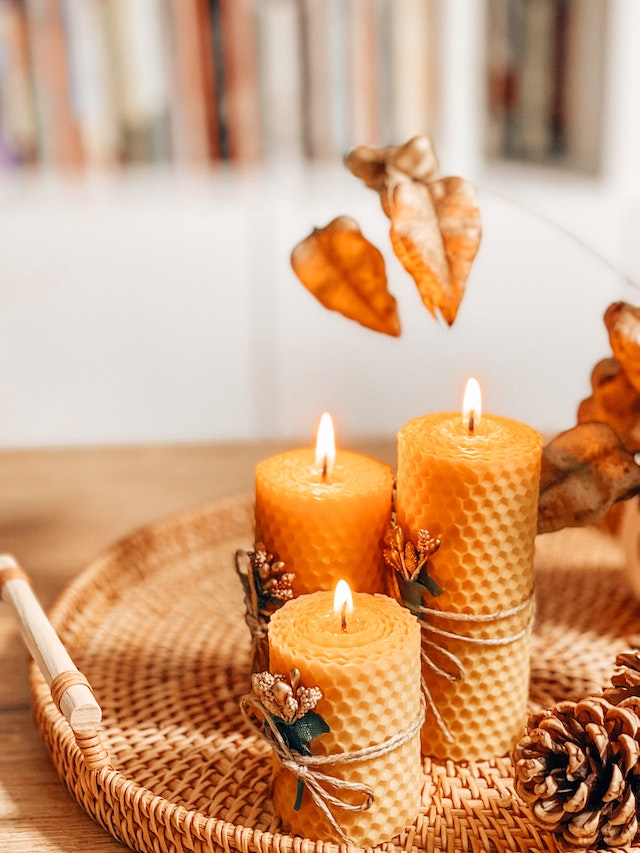 autumn decoration with beeswax candles pine cones and leaves on wicker tray