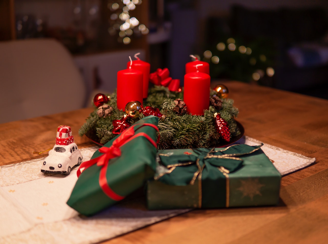 unlighted red advent candles on table beside green gift boxes