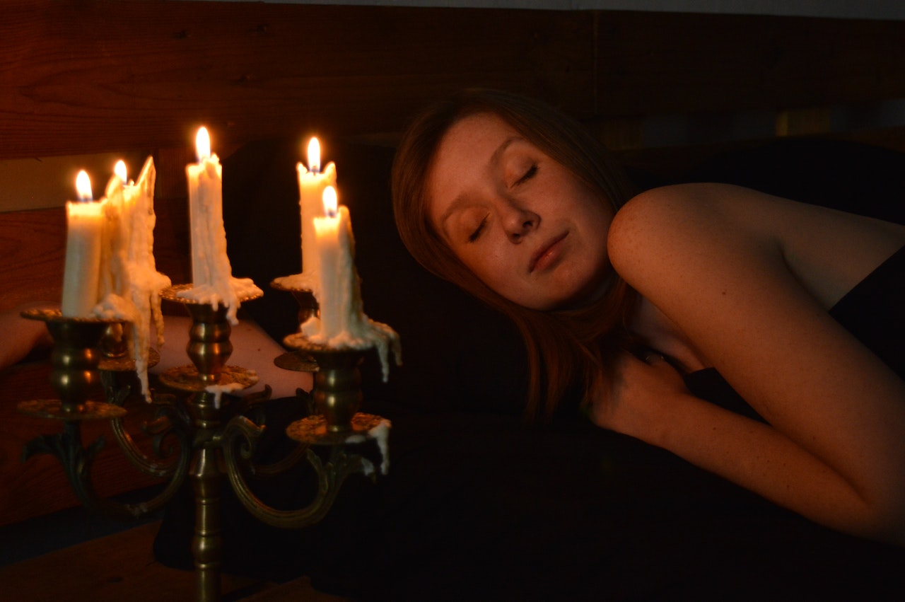 woman asleep next to burning candles 