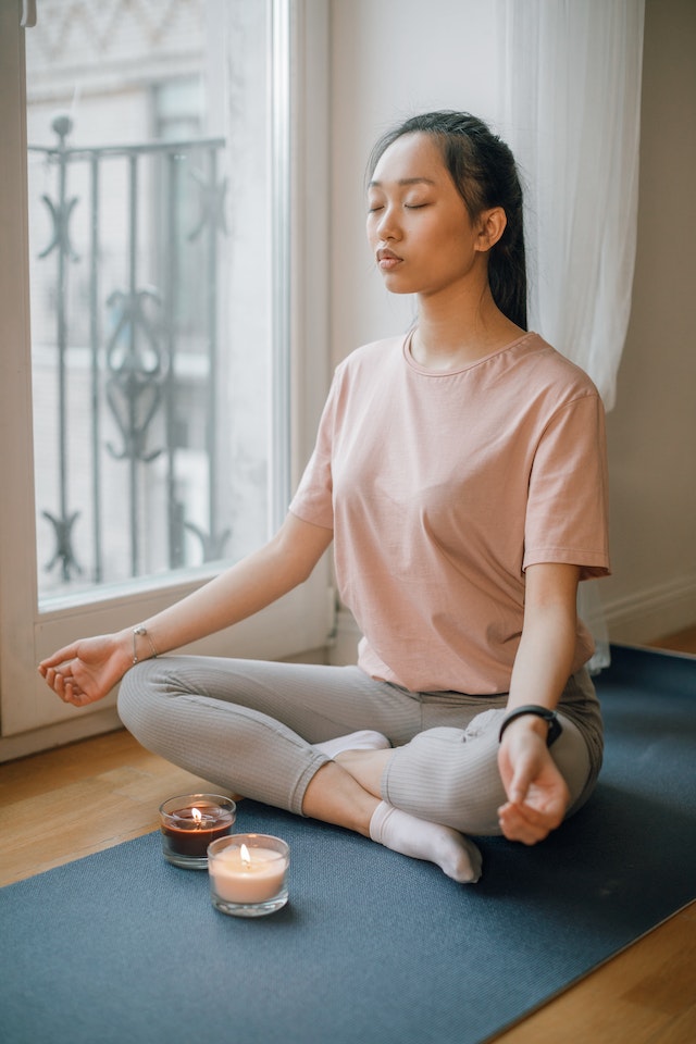 woman sitting near the candle while meditating